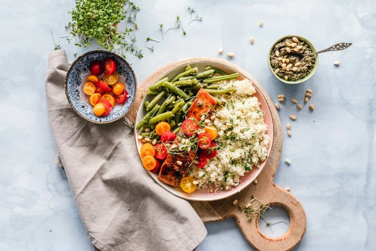 Roasted fish, grains and colourful vegetables on a ceramic plate